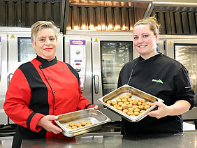 Zwei Frauen mit je einer Schale Bällchen.