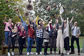 Viele Menschen werfen einen Hut.