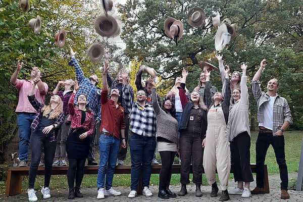 Viele Menschen werfen einen Hut. 