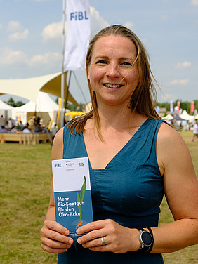 Frau schaut in die Kamera, dahinter Zelte einer Outdoor-Messe.