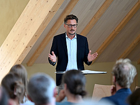 Mann steht an einem Pult und hält einen Vortrag.