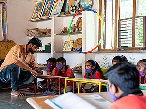 A man and six children in a classroom.