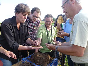 Gruppe von Personen untersucht eine Bodenprobe.