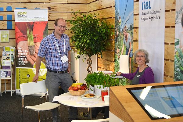 [Translate to Englisch:] Two people standing at an information booth