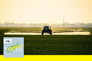 Ein Traktor mit einer Feldspritze auf einem Feld.