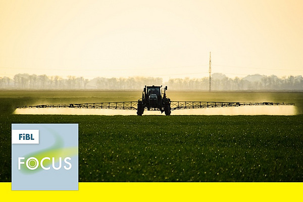 Ein Traktor mit einer Feldspritze auf einem Feld.