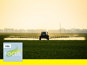 Ein Traktor mit einer Feldspritze auf einem Feld.