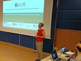 A woman in front of a screen with a presentation. 