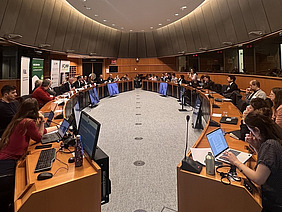 Two opposing rows of podiums with people.