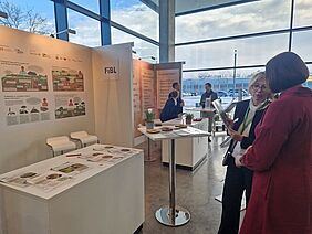 Two women talking in front of a stand.