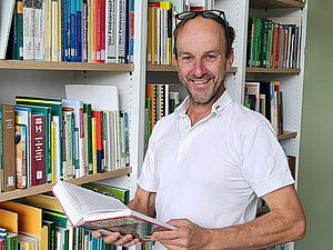 Andreas Gattinger mit aufgeschlagenem Buch in den Händen.