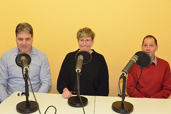 Urs Brunner, Anna Lehman und Urs Knecht sitzen an den Podcast-Mikrofonen