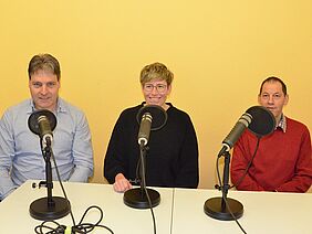 Urs Brunner, Anna Lehman und Urs Knecht sitzen an den Podcast-Mikrofonen