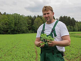 Mann am Acker mit Pflanzen in der Hand