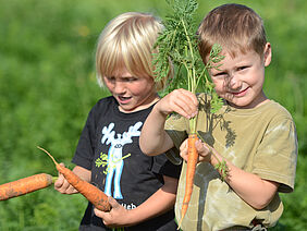 Kinder mit geernteten Karotten
