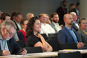 The picture shows an audience sitting in rows, looking intently towards the front.
