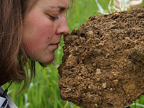 A woman is assessing the smell of a soil sample