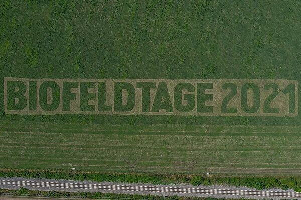 Wiese mit eingemähtem Schriftzug "Biofeldtage 2021"