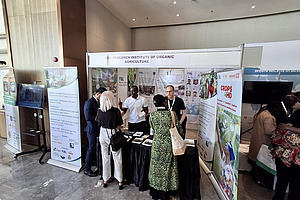Two men at a stand with people gathering.