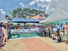 Gruppenfoto in U-Form, in der Mitte halten Menschen ein Banner.
