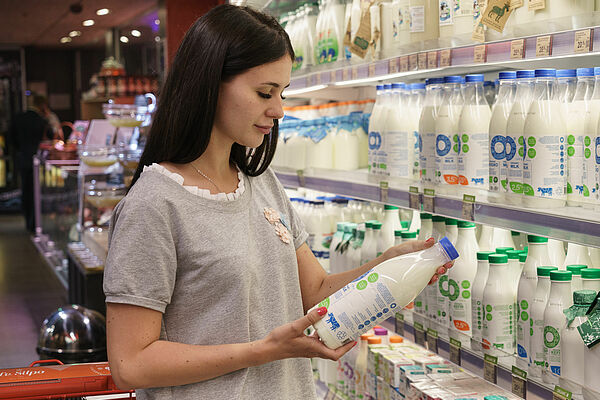 Woman looking at milk bottle in supermarket.