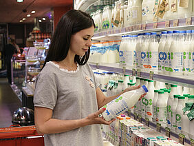 Woman looking at milk bottle in supermarket.
