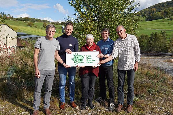 Four men and a woman in front of a green background holding a sign with the SPBC logo.